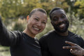 Portrait of smiling athletic man and woman taking selfie in park