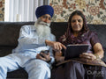 Senior couple in traditional clothing using phone and tablet at home