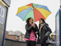 Cheerful women under umbrella on boat