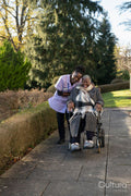 Nurse and senior woman in wheelchair going on walk in park
