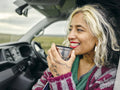 Woman sitting in van and drinking from insulated drink container