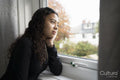 Thoughtful teenage girl looking through window