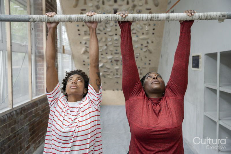 Mother and daughter doing chin-up exercise on bar
