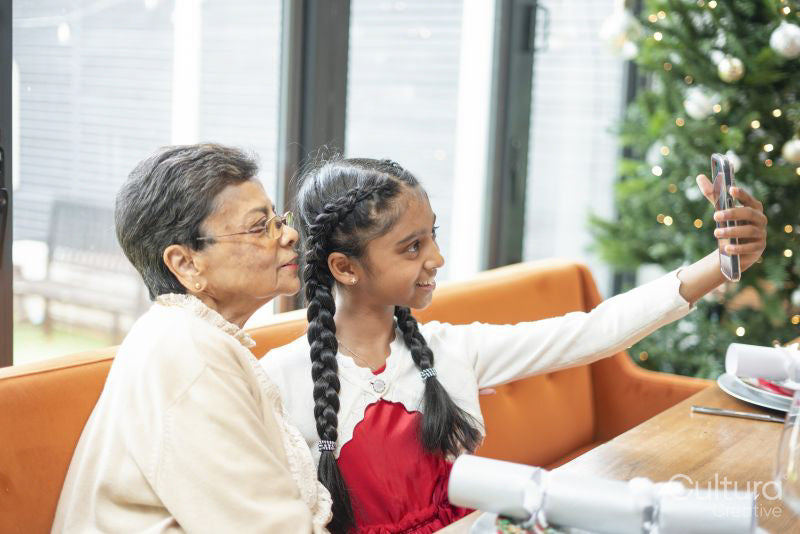 Smiling girl with grandmother taking selfie at table