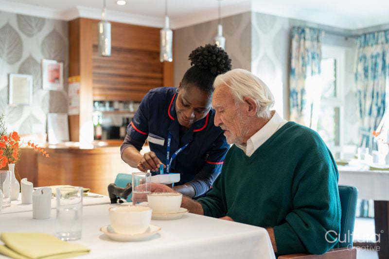 Nurse giving medicine to senior man in nursing home