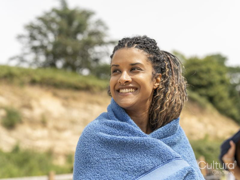 Portrait of smiling woman wrapped in towel on beach