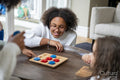 Smiling sisters playing tic tac toe at home