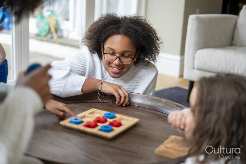 Smiling sisters playing tic tac toe at home