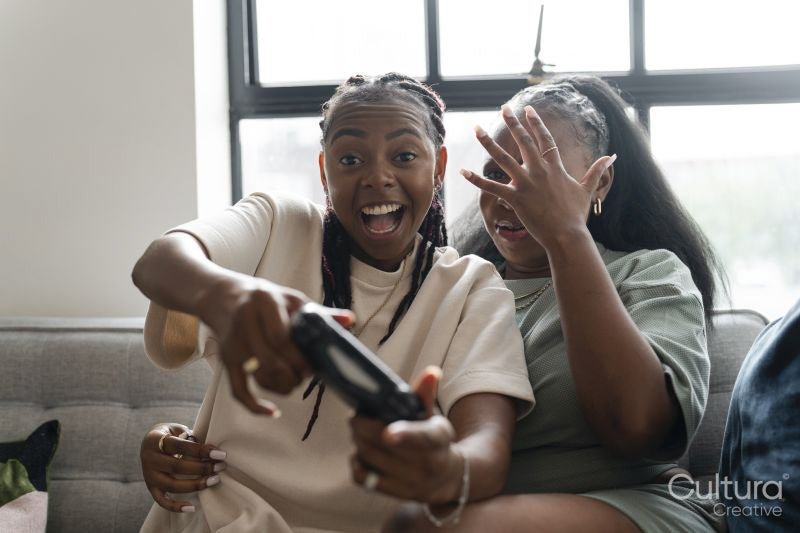 couple playing video games while sitting on sofa at home