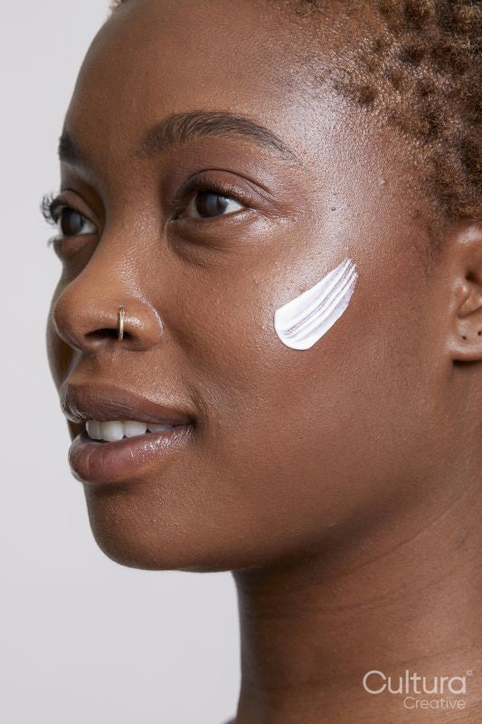 Close-up of smiling woman with face cream on cheek