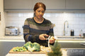 Woman peeling parsley root in kitchen