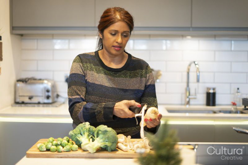 Woman peeling parsley root in kitchen