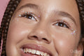 Close-up of smiling girl with decorative stickers on face