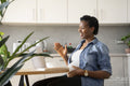 Smiling pregnant woman having video call via laptop in kitchen