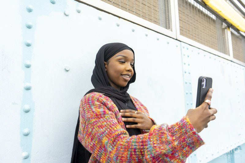 Smiling young woman wearing hijab taking selfie