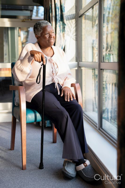 Senior woman with walking cane looking through window