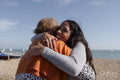 Mother and daughter embracing on beach on sunny day
