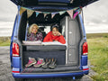 Women lying in back of van and looking at view