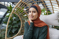 Portrait of woman wearing headscarf sitting in swing chair