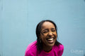 Young woman in pink sweatshirt laughing outdoors