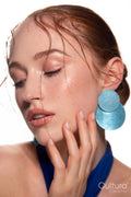 Studio portrait of a woman in a blue dress and large blue earrings
