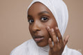 Studio portrait of young woman in white hijab touching face