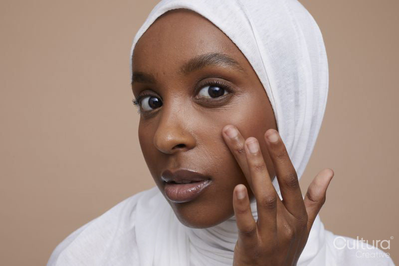 Studio portrait of young woman in white hijab touching face