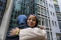 Two women wearing hijabs hugging in street