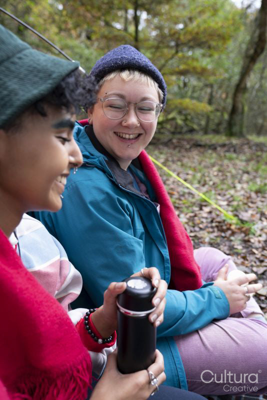 Smiling female friends camping in forest