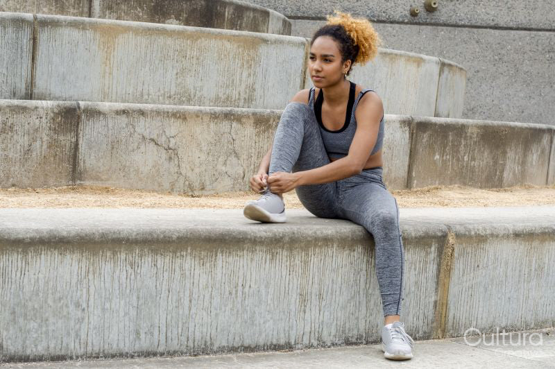 Woman tying laces in sports shoes before training