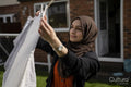 Woman wearing hijab hanging laundry in backyard