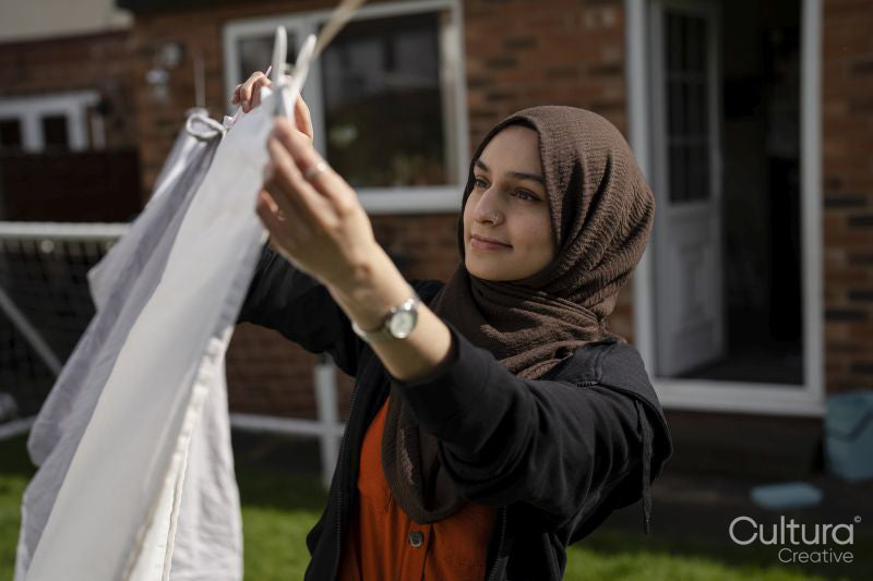 Woman wearing hijab hanging laundry in backyard