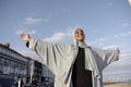 Portrait of smiling Muslim woman standing with arms outstretched on sunny day