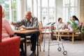 Senior people and care giver hanging out in common room in nursing home