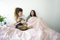 Two women and dog relaxing on bed