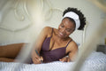 Smiling woman in lingerie writing in notebook on bed