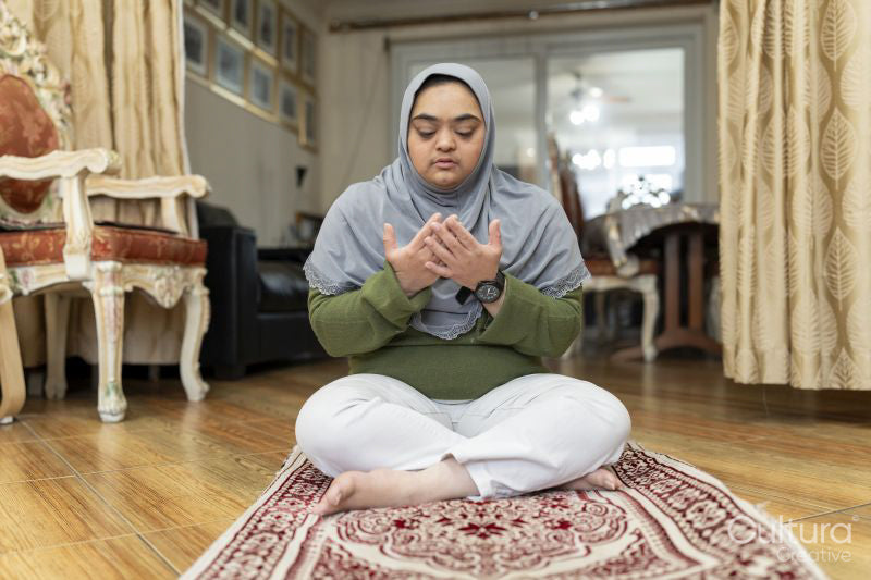 Muslim woman with down syndrome praying at home