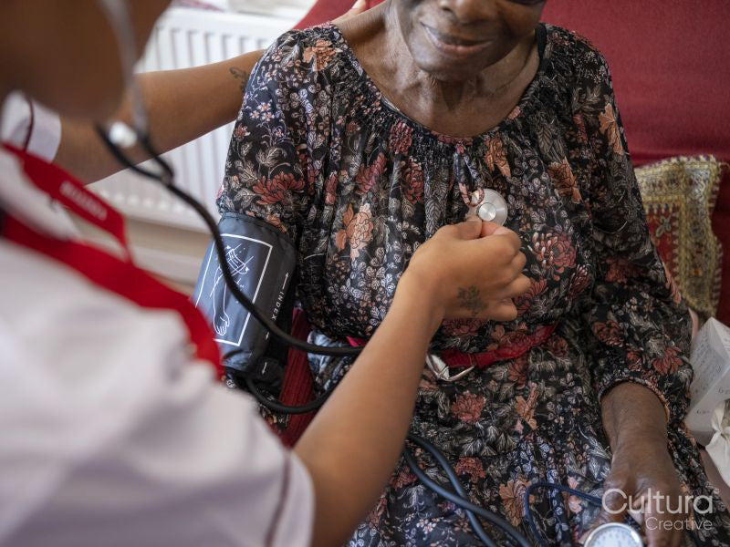 Nurse taking care of elderly woman, examining chest with stethoscope