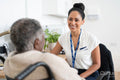 Smiling female doctor talking to senior woman sitting in wheelchair