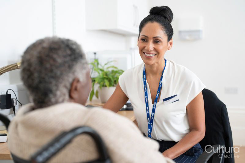 Smiling female doctor talking to senior woman sitting in wheelchair