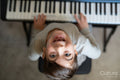 Boy playing music keyboard at home, view from above