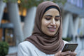 Smiling businesswoman in hijab looking at smart phone