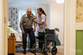 Nurse helping senior man to sit on wheelchair at nursing home