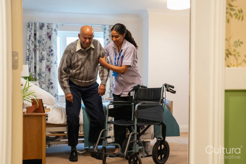 Nurse helping senior man to sit on wheelchair at nursing home