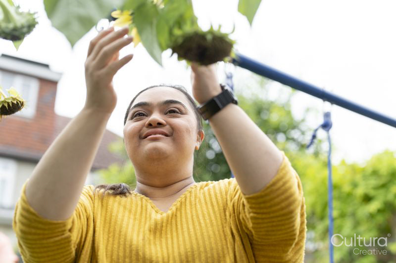 Young woman with down syndrome touching flower in garden