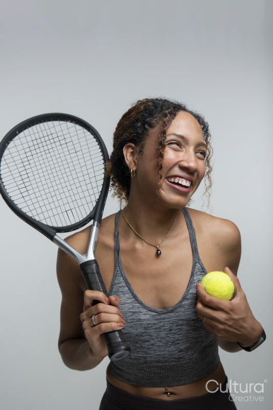 Smiling woman holding tennis racket and ball