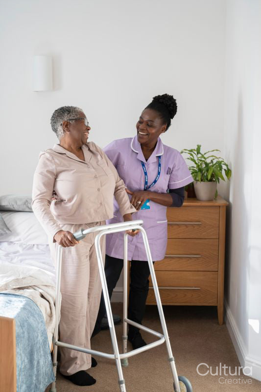 Caregiver assisting smiling senior woman with mobility walker in bedroom
