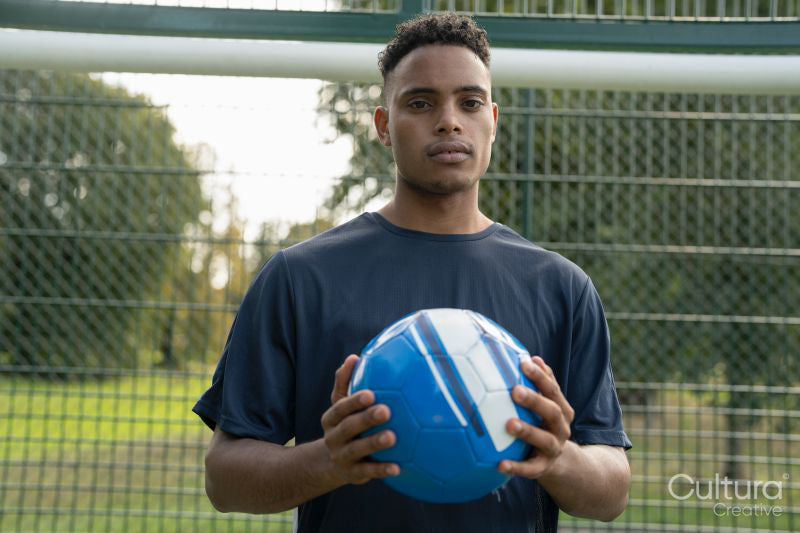 Portrait of man standing with soccer ball outdoors