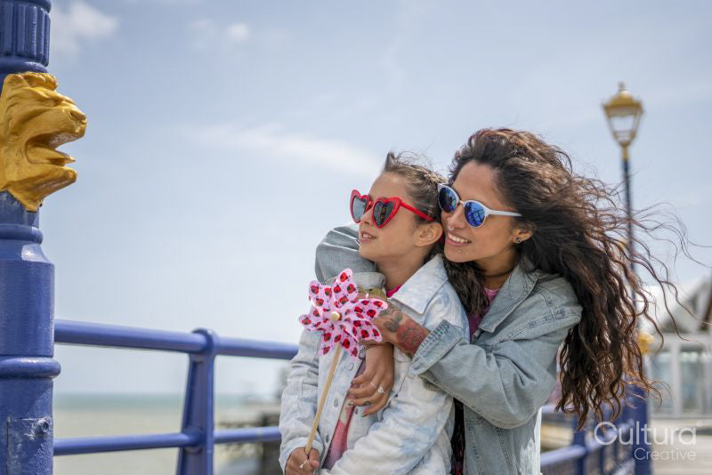 Smiling mother and daughter hugging on promenade