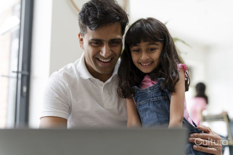 Father sitting with daughter and using laptop